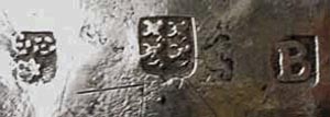 Merktekens op de onderzijde van het oudste stuk 'Schoonhovens' zilver'. Links het teken van de onbekende meester 'twee rozen met een ster', het stadteken, de bekende vier klimmende leeuwen, en uiterst rechts de 'jaarletter'.